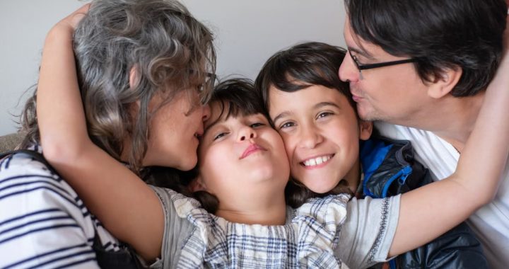 A joyful family of four sharing a warm embrace, highlighting love and togetherness indoors.